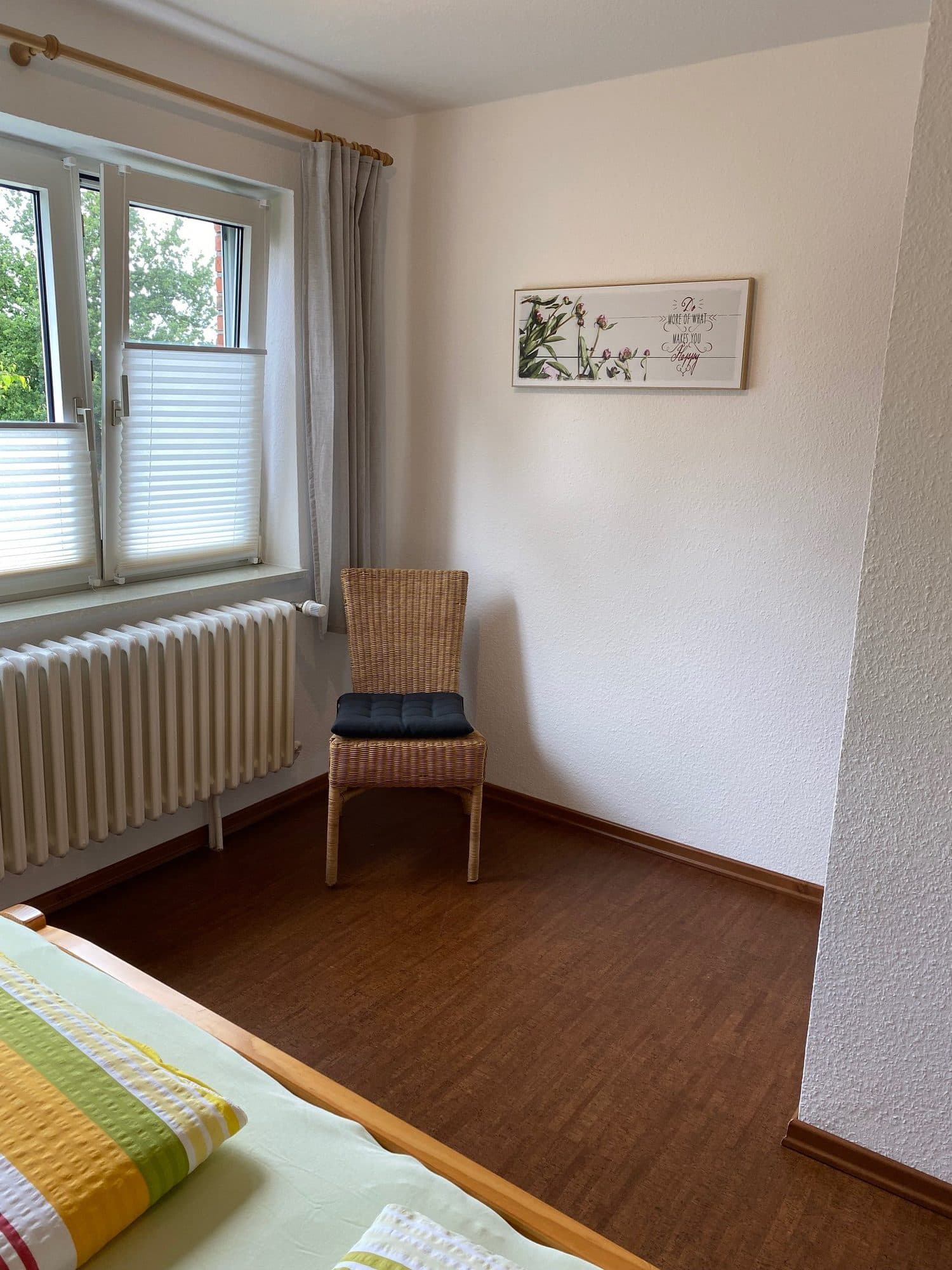 Schlafzimmer mit Korbsessel am Fenster