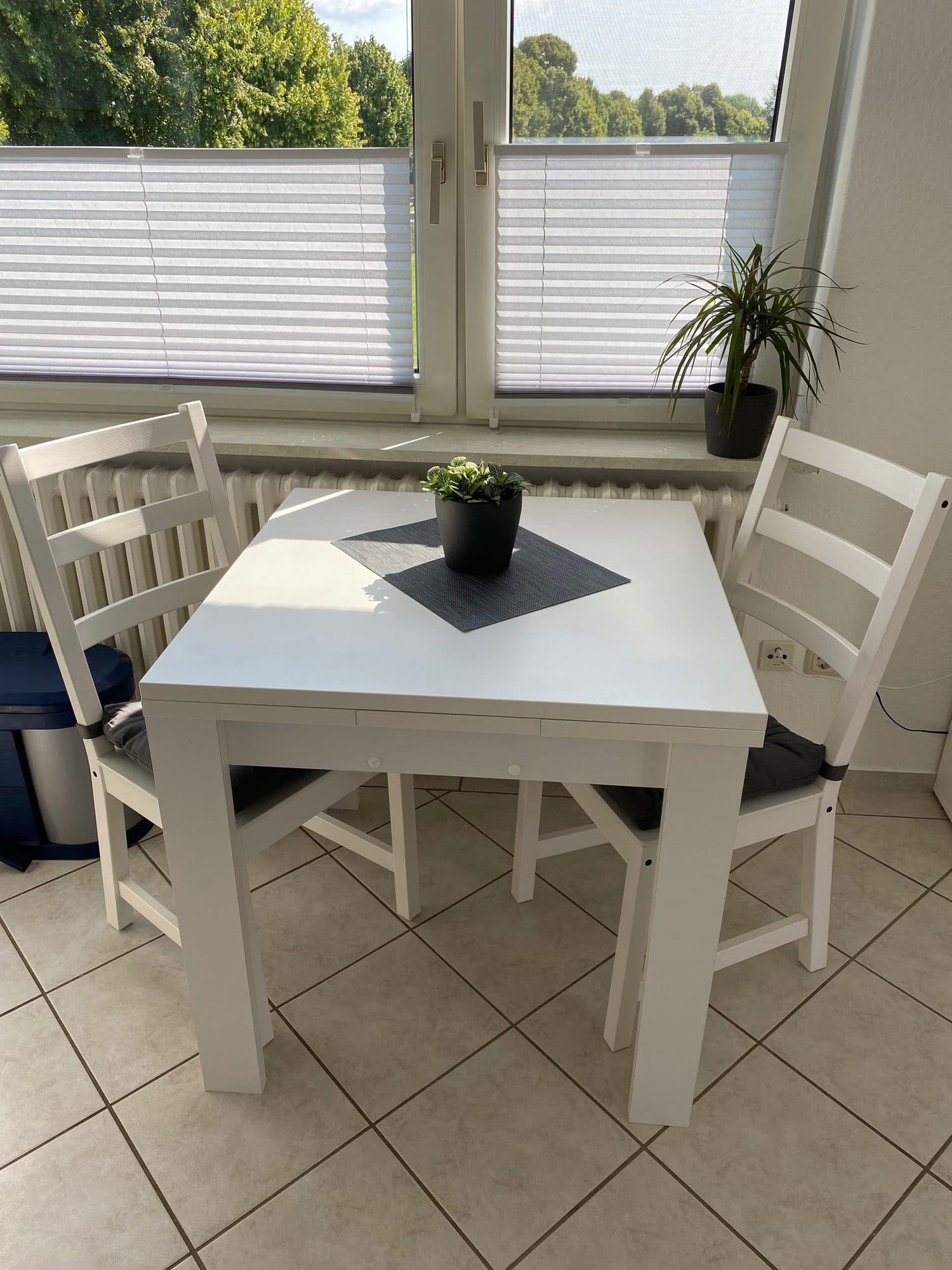 Essplatz mit weißem Tisch und vier Stühlen am Fenster