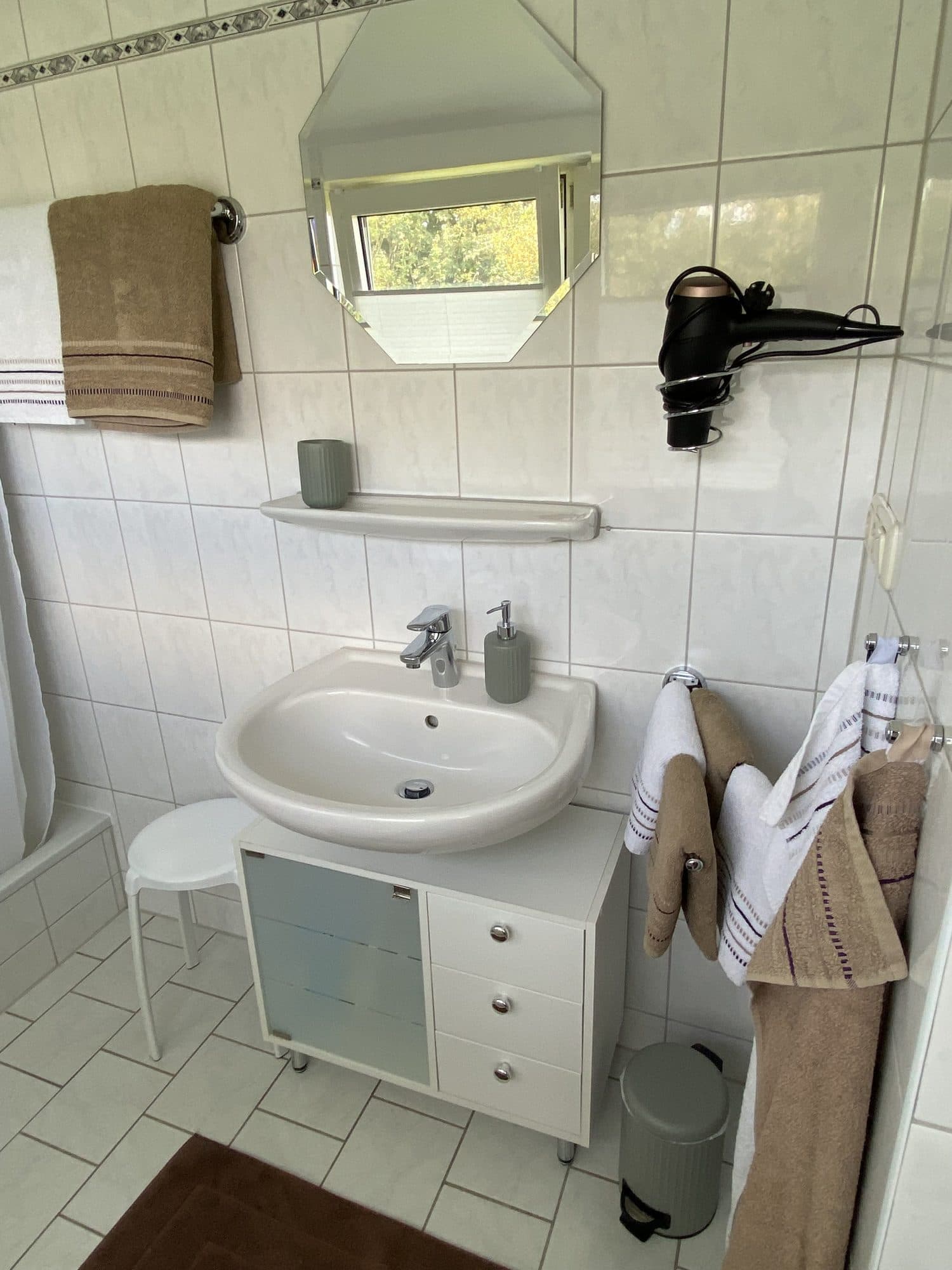 Waschbecken mit Spiegel, Föhn und Handtüchern