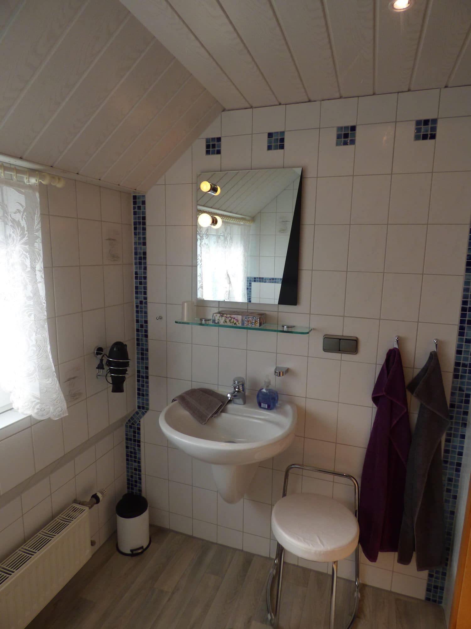 Bad mit Waschbecken, Spiegel und Hocker unter der Dachschräge