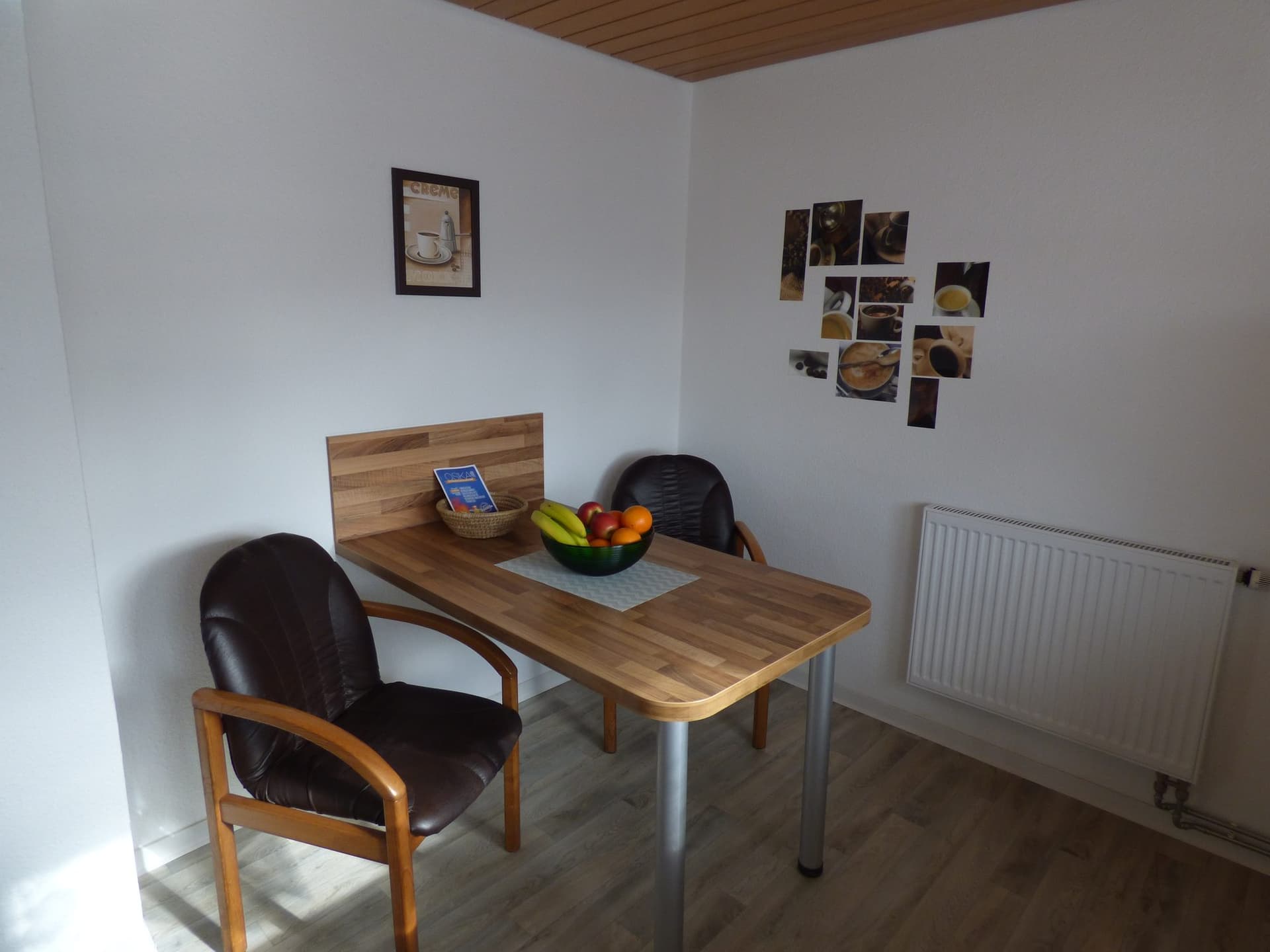 Essplatz mit Holztisch, zwei Stühlen und Fotos an der Wand