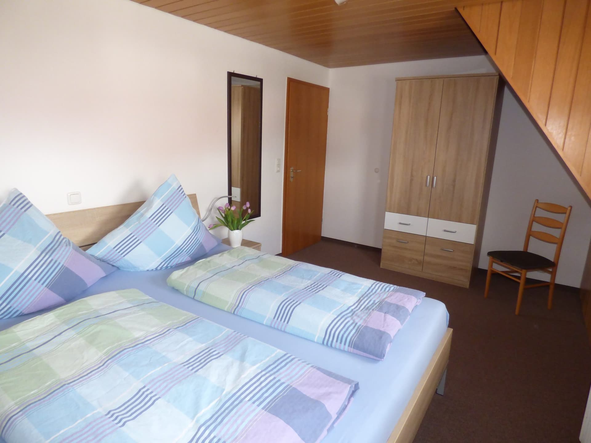 Schlafzimmer mit Doppelbett, Kleiderschrank und Dachschräge