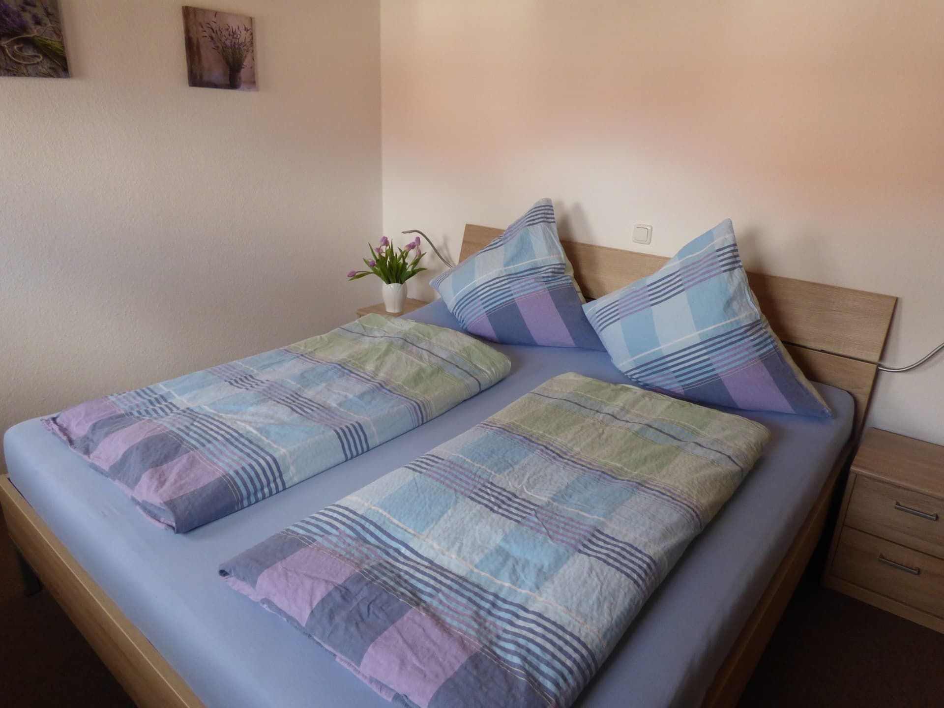 Doppelbett mit heller Bettwäsche unter der Dachschräge