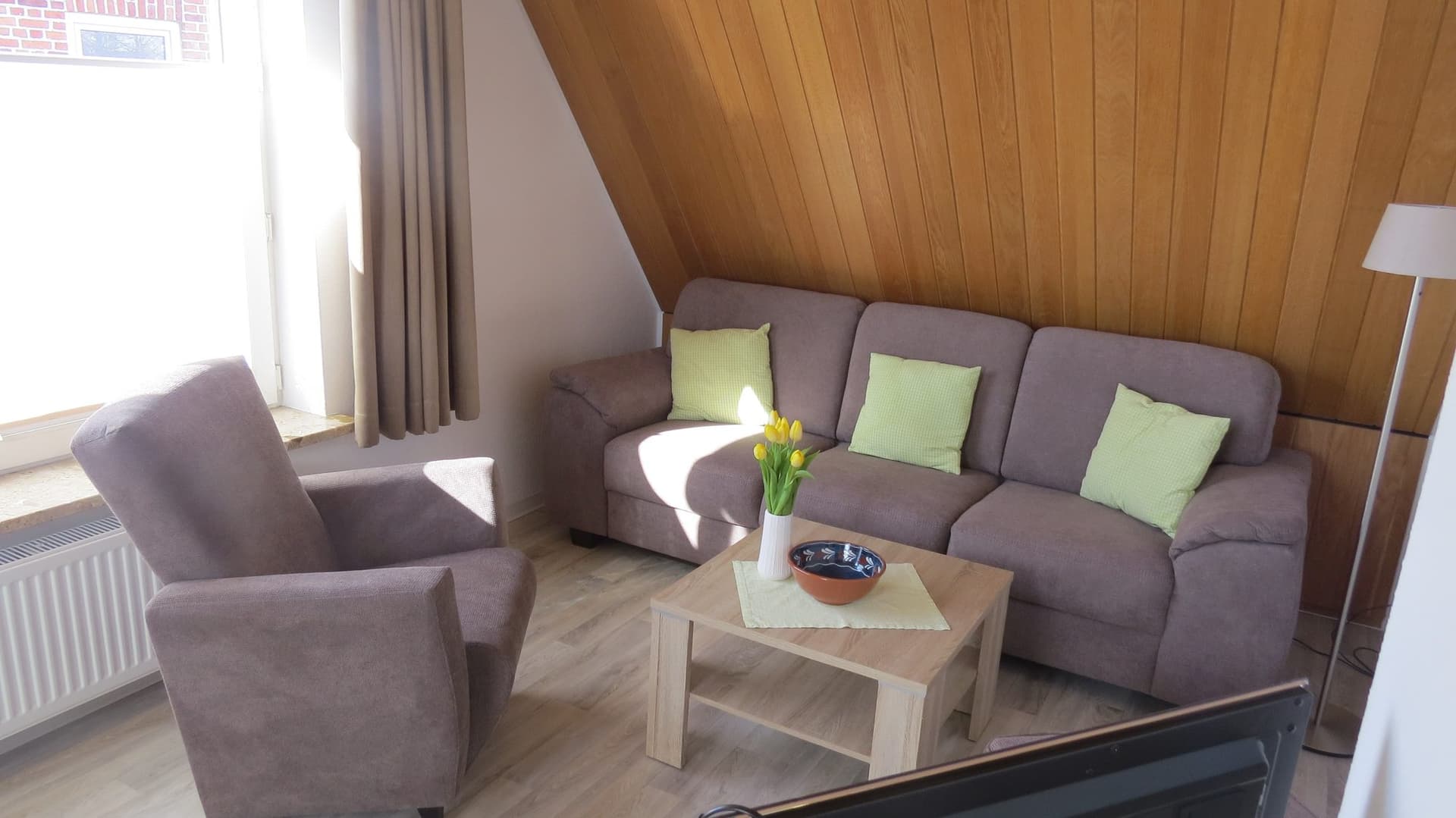 Sitzecke mit Sofa und Sessel unter der Holzdecke