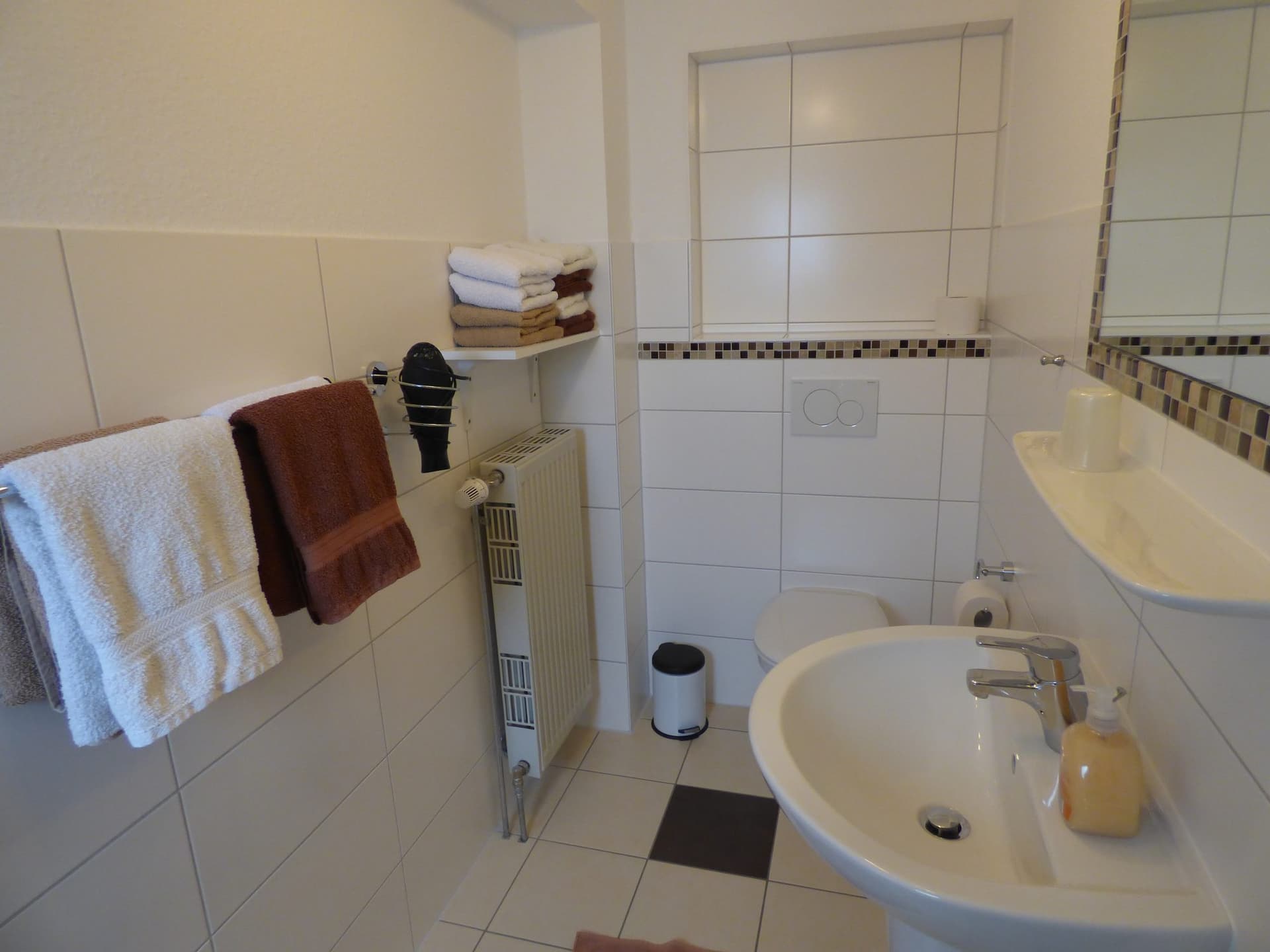 Waschbecken mit Handtüchern und Mosaikbordüre