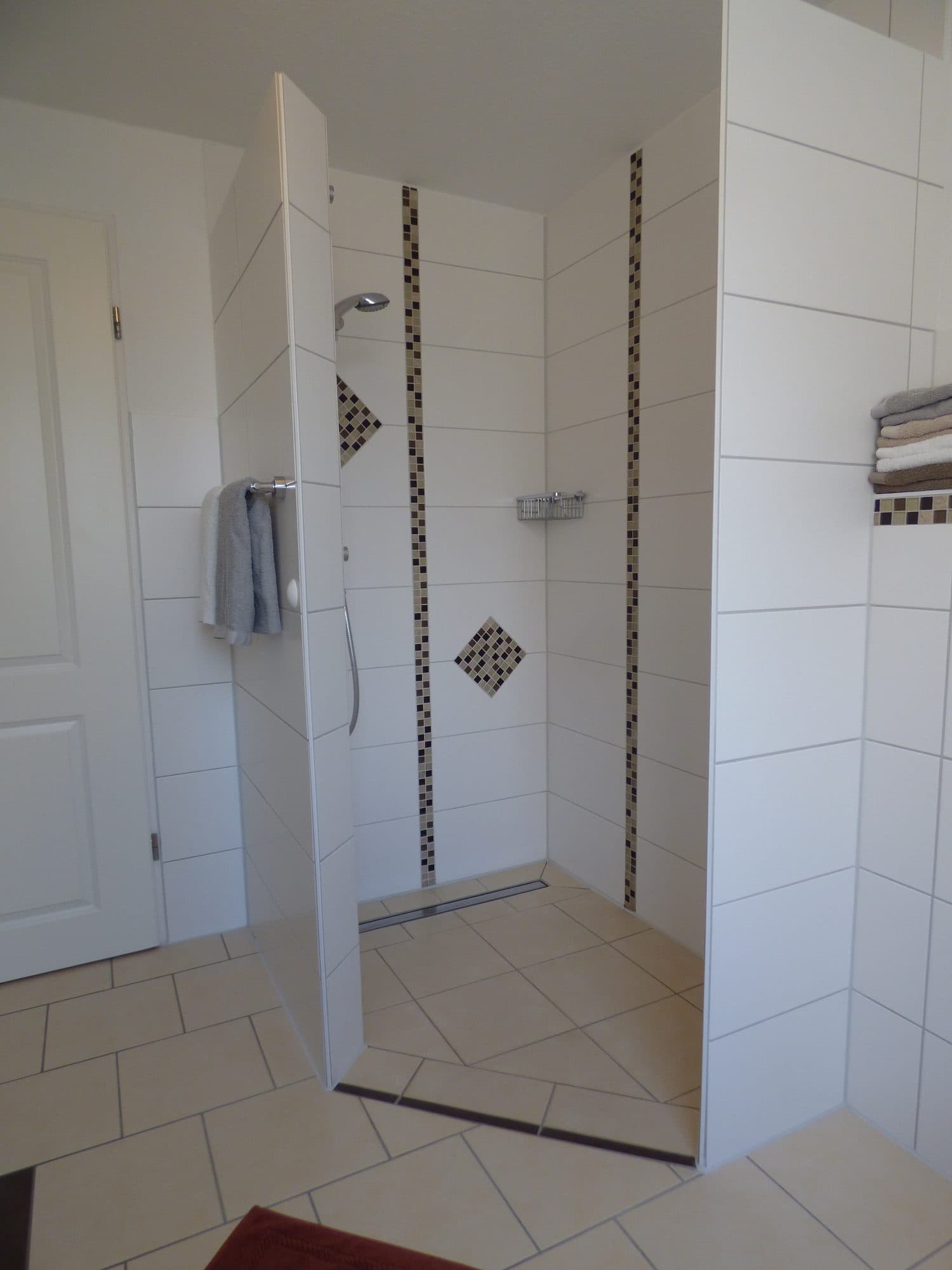 Dusche mit Glastür im gefliesten Bad