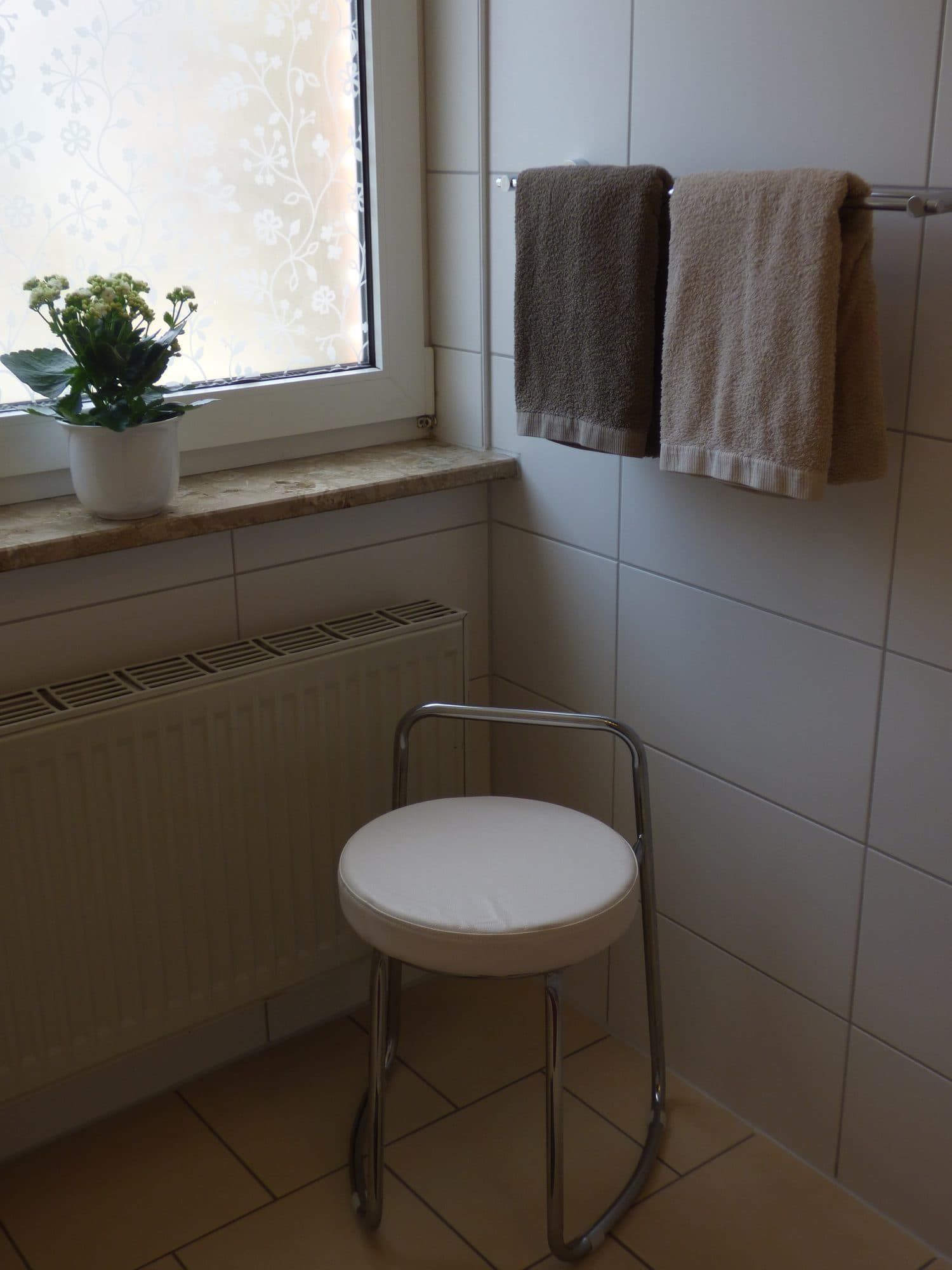 Bad mit Hocker und Handtuchhalter am Fenster