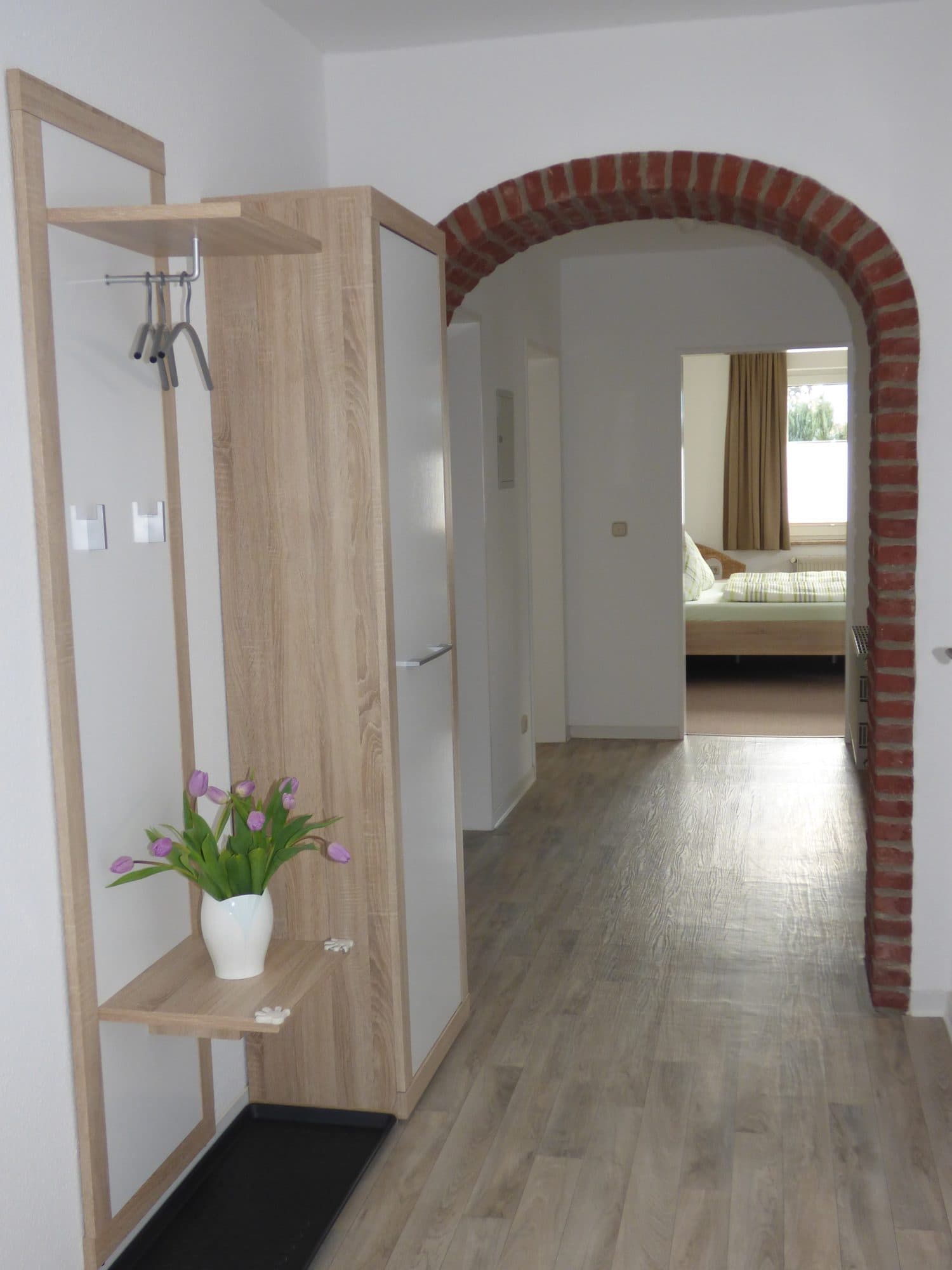 Flur mit Garderobe und gemauertem Rundbogen