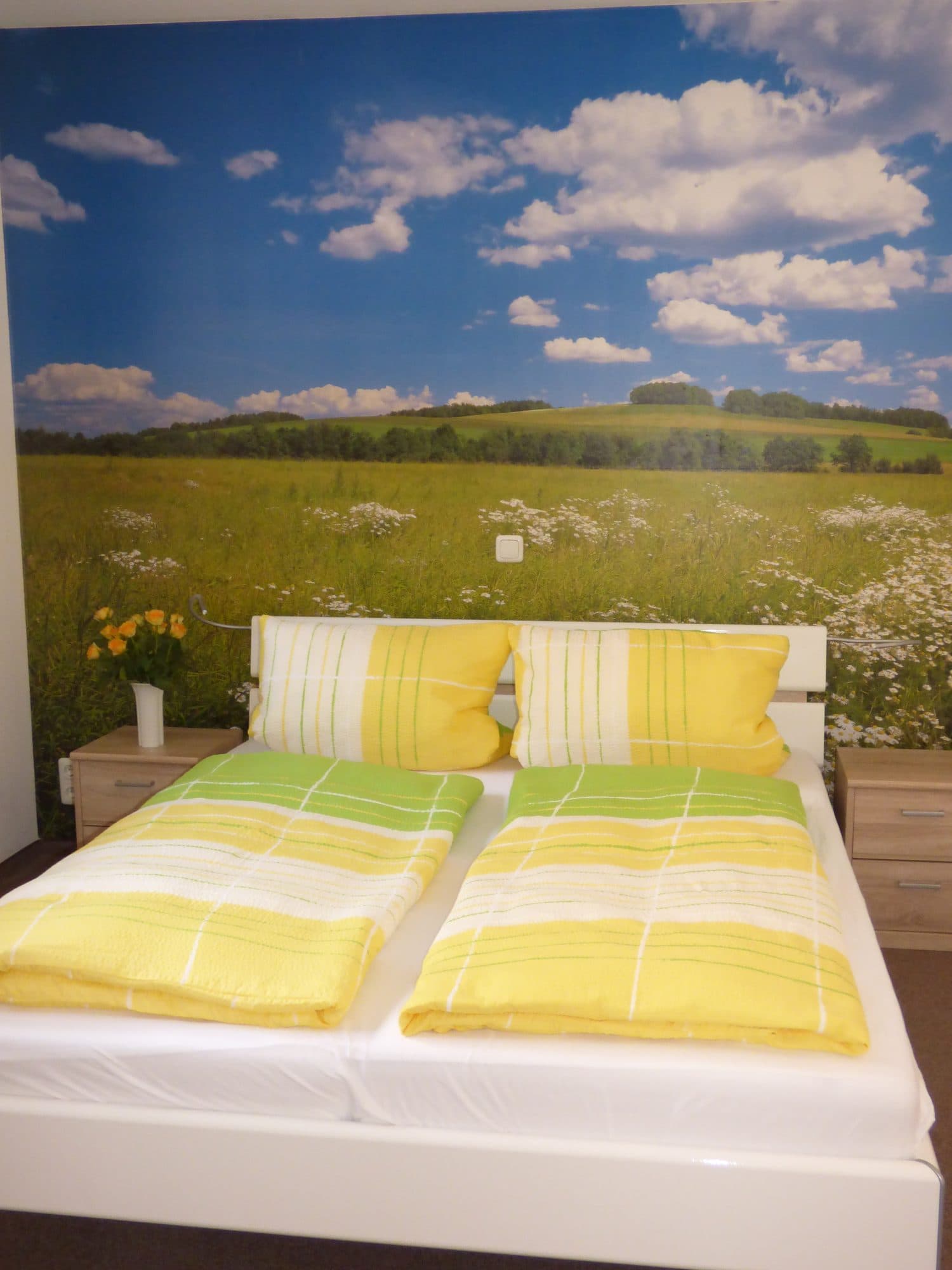 Schlafzimmer mit Wiesen-Fototapete und gelber Bettwäsche